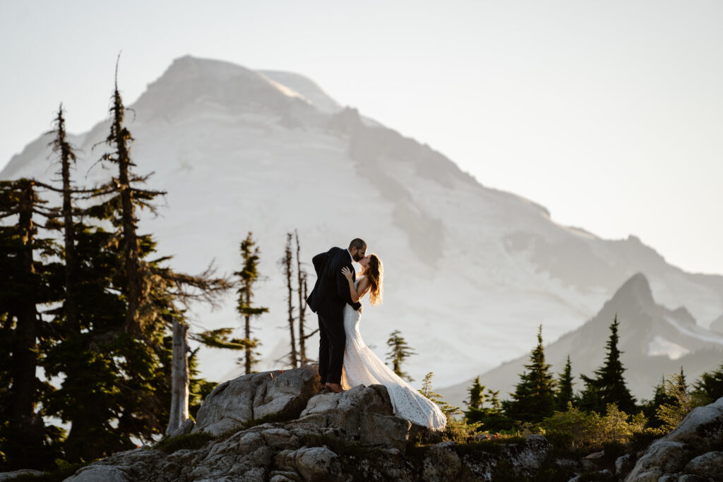 a couple in wedding attire kiss on a ridge in front of mount baker during their north cascades elopement