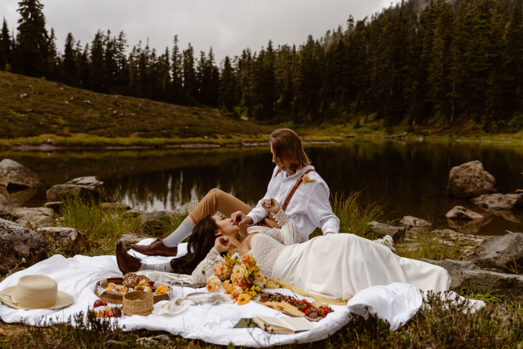 a bride and groom relax and eat snacks on a picnic blanket during their north cascades elopement