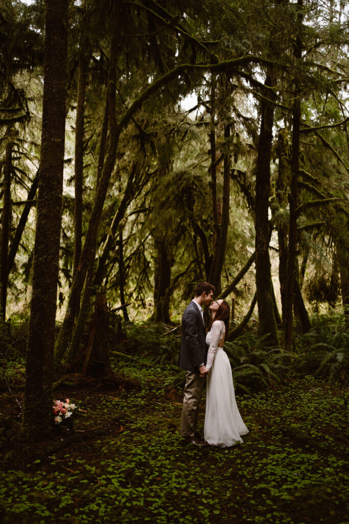 a bride and groom embrace in a grove of trees in the olympic national forest