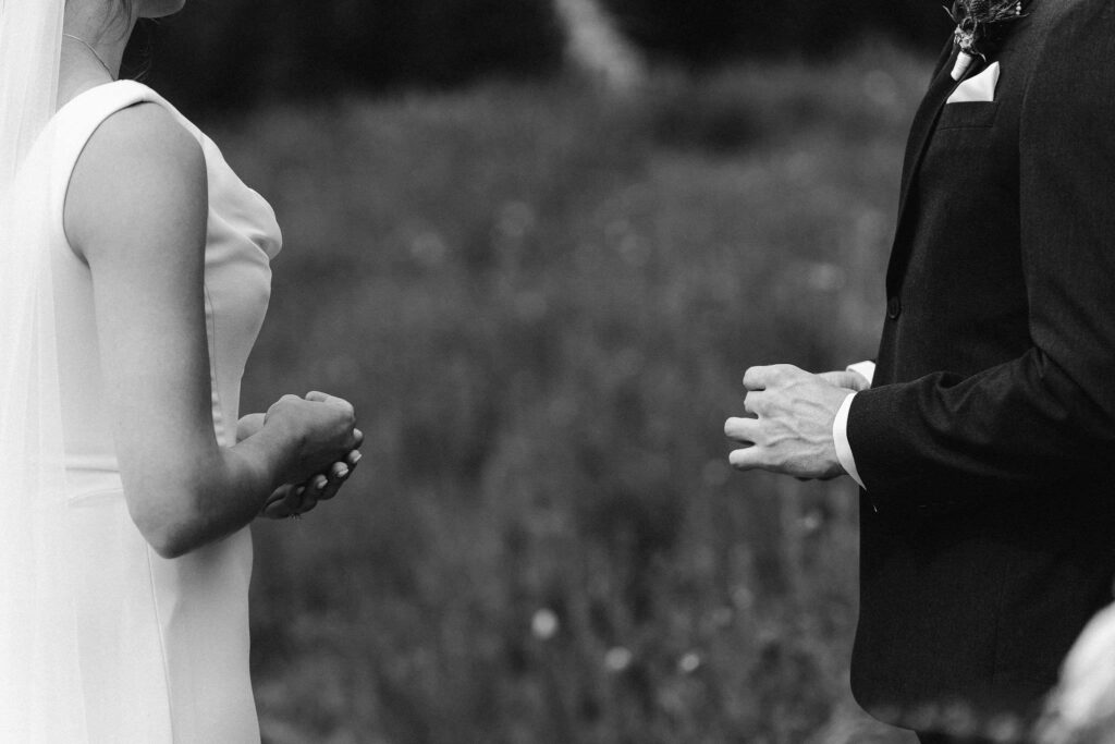 a bride and groom hold each other's rings during a mt rainier elopement ceremony