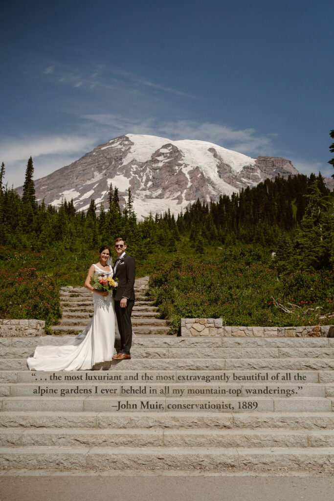 a bride and groom pose on the Paradise steps with a John Muir quote during their mount rainier micro wedding