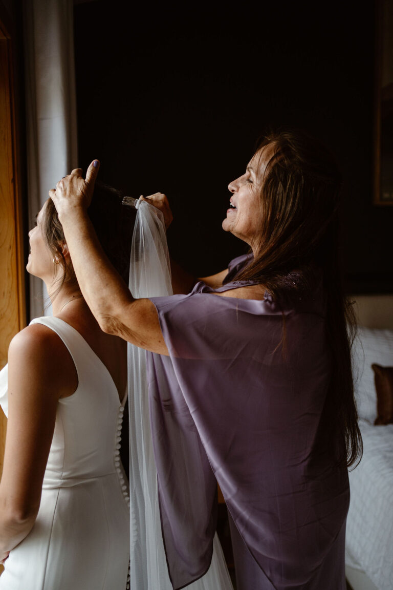 the bride's mom helps put her veil in while getting ready for a mt rainier micro wedding reception dinner