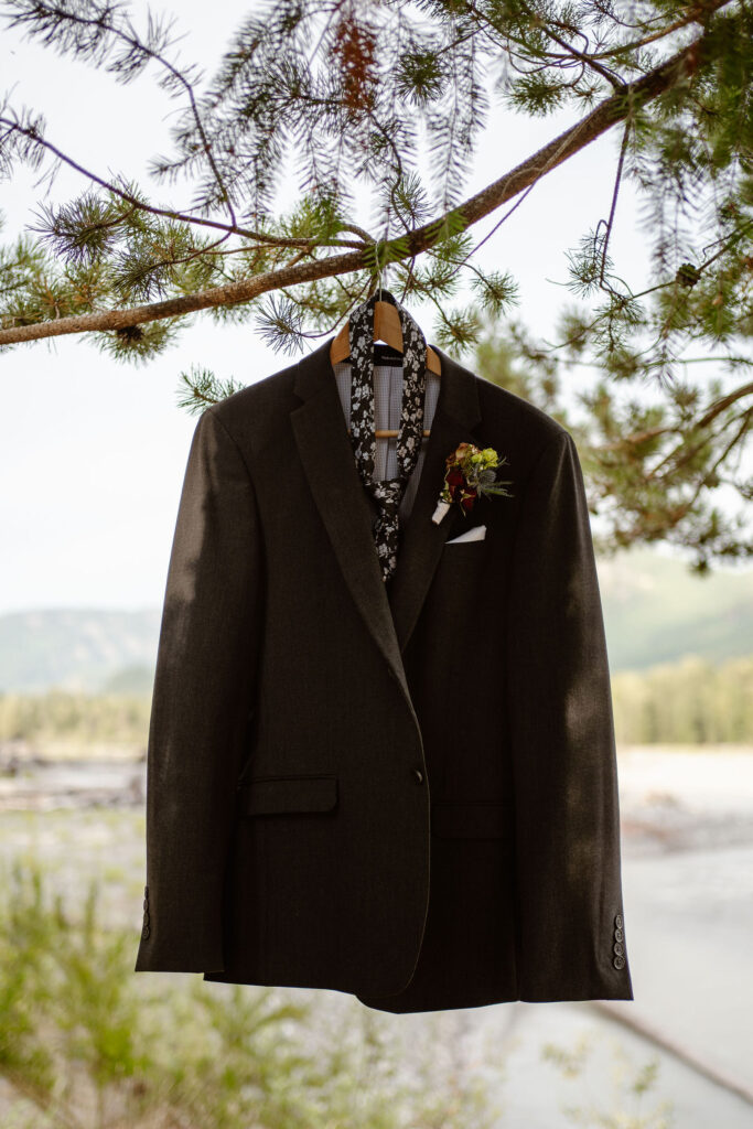 a groom's suit jacket & tie hang on a tree with the cowlitz river in the background
