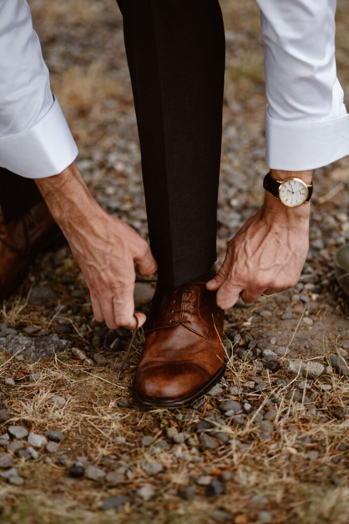 a groom puts his shoes on while getting ready for his mt rainier micro wedding reception dinner