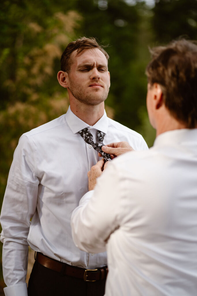 the groom's dad helps with his tie while getting ready for a mt rainier micro wedding reception dinner