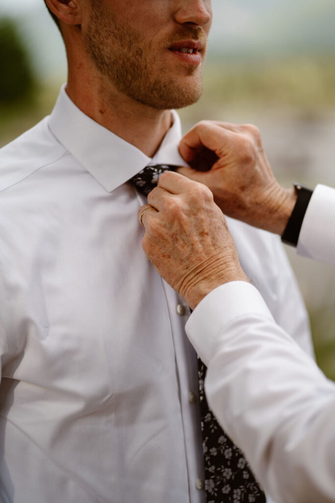 the groom's dad helps with the groom's tie while getting ready