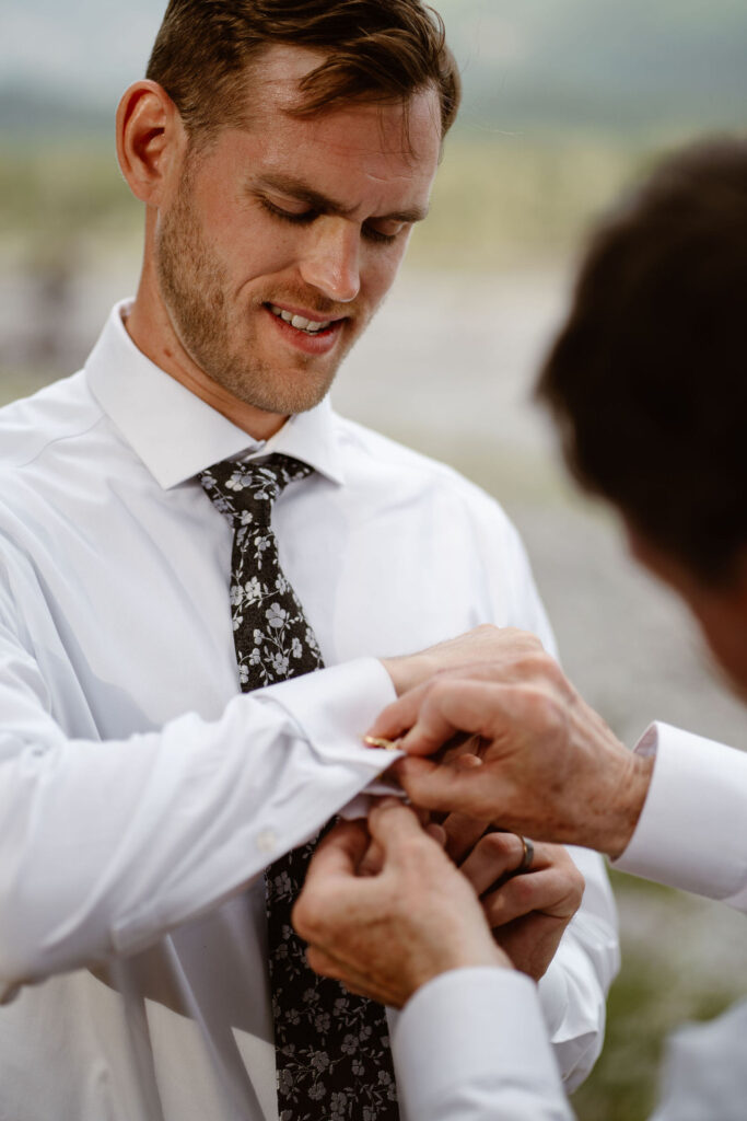 a groom's dad helps with his cufflinks while getting ready for a mt rainier micro wedding reception dinner