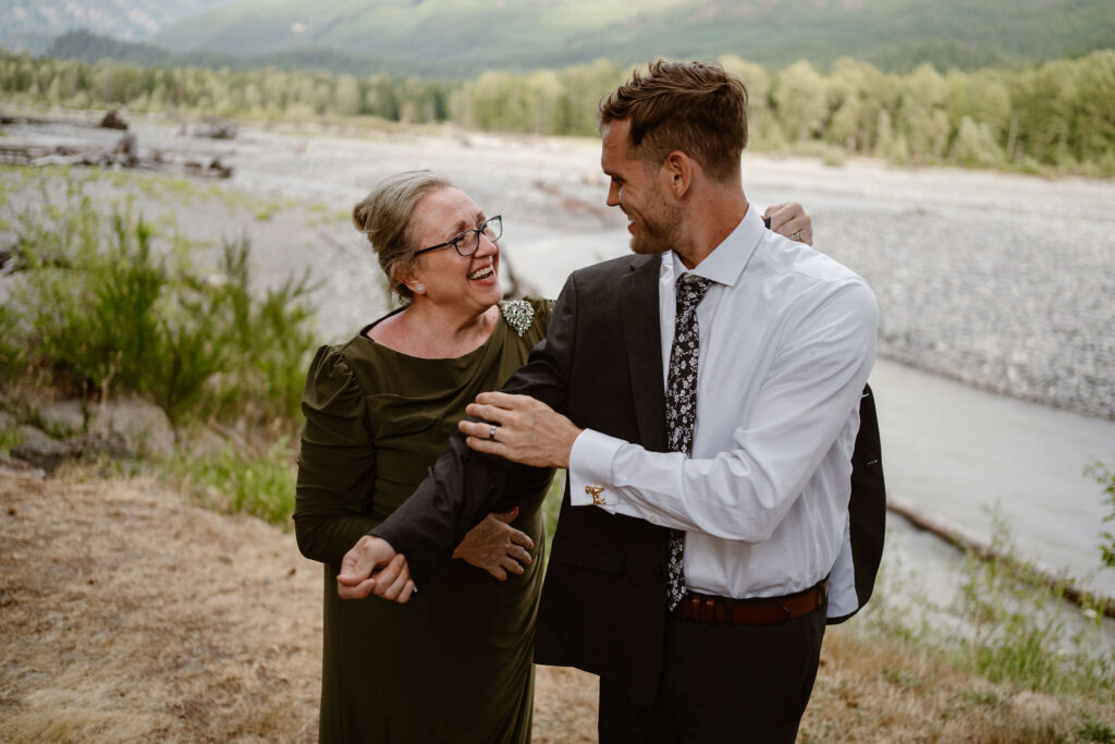the groom's mother helps him put his jacket on with the cowlitz river in the background