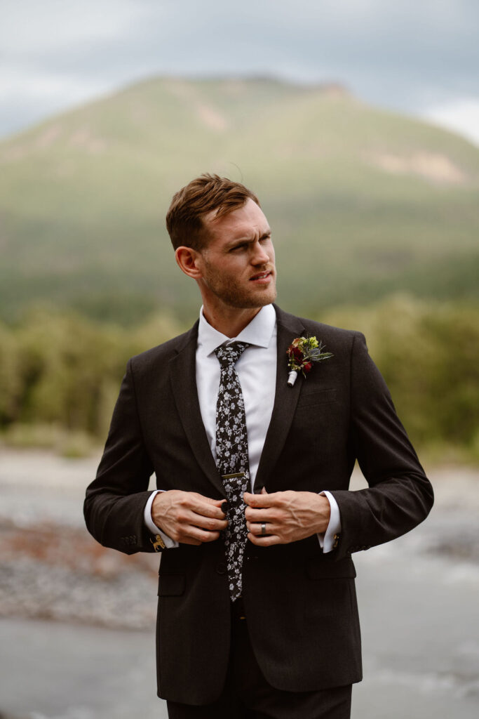 a groom buttons his jacket while getting ready for his mt rainier micro wedding reception dinner