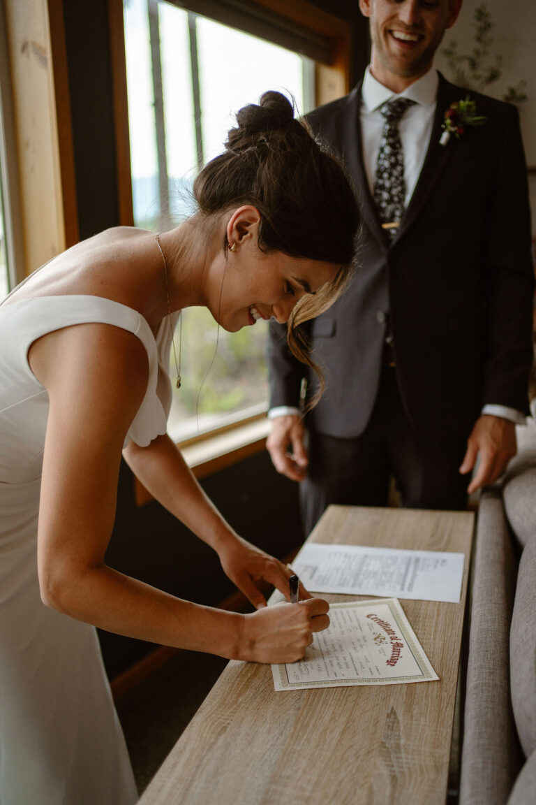 a bride signs her marriage license during a mt rainier micro wedding
