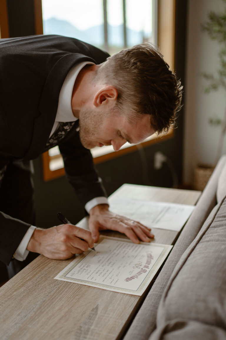 a groom signs his wedding license during a mount rainier micro wedding