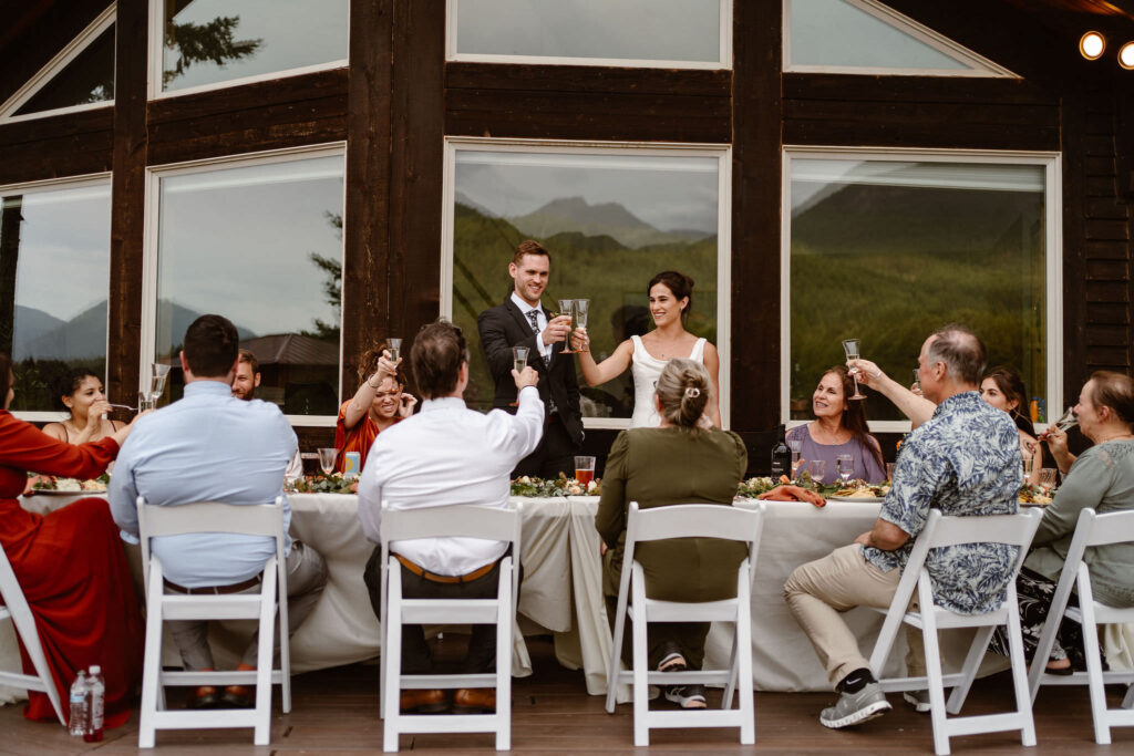 a bride and groom toast while their families raise their glasses during a mt rainier micro wedding reception dinner