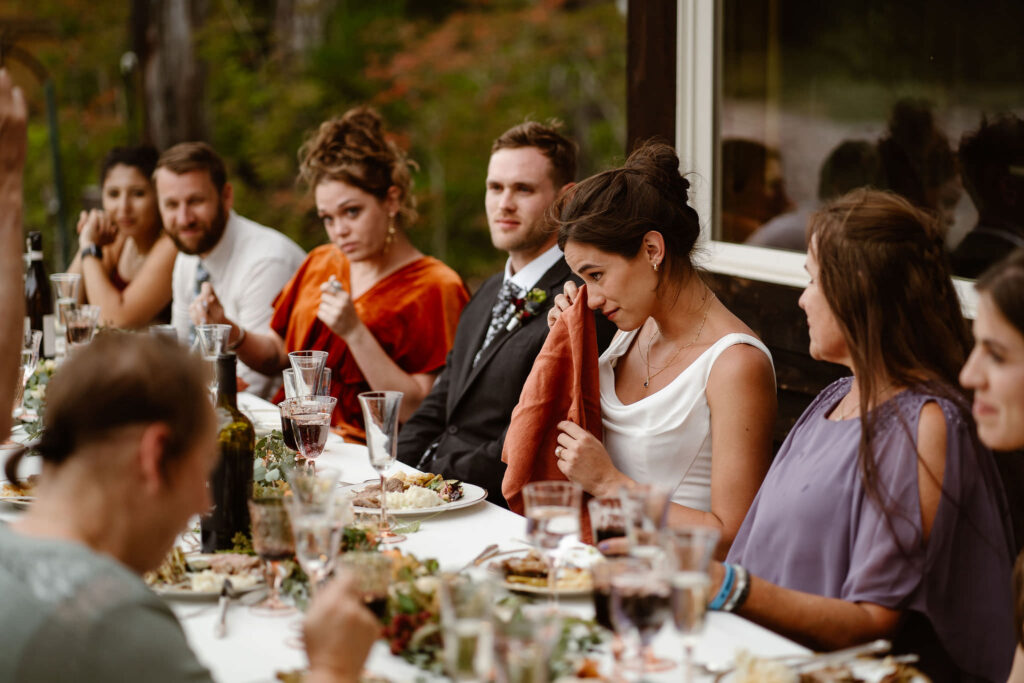 a bride wipes away tears during a mt rainier micro wedding reception dinner