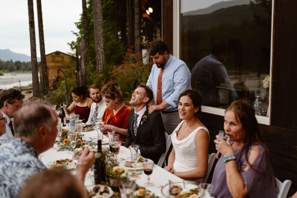the bride's brother squeezes the groom's shoulders during a mt rainier micro wedding reception