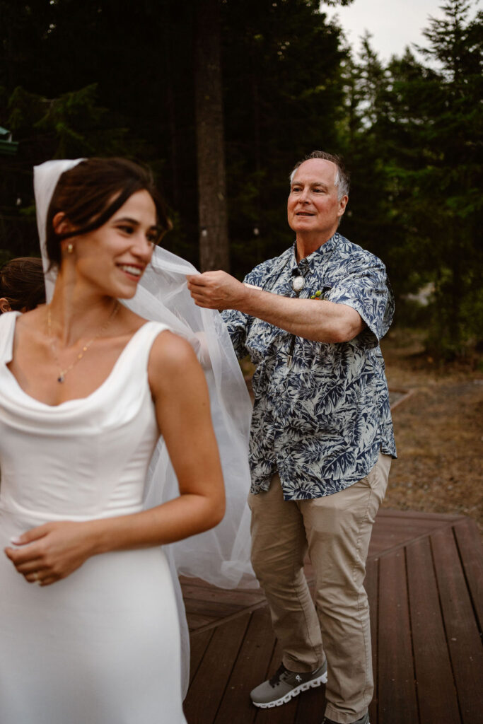 the bride's dad helps adjust her veil during a mount rainier micro wedding