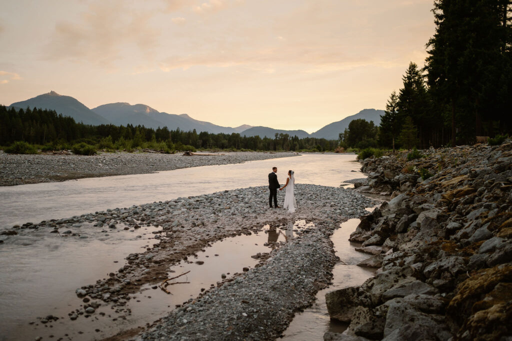 a bride and groom pose along the cowlitz river at sunset during their mount rainier micro wedding