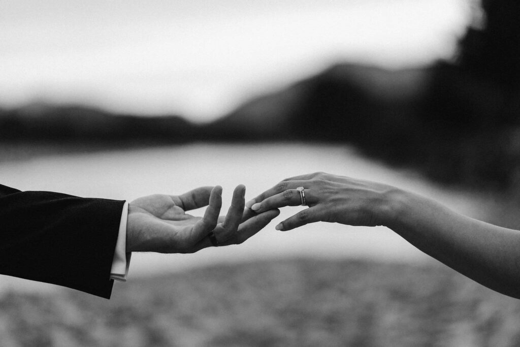 black & white close-up of a bride and groom extending hands towards each other